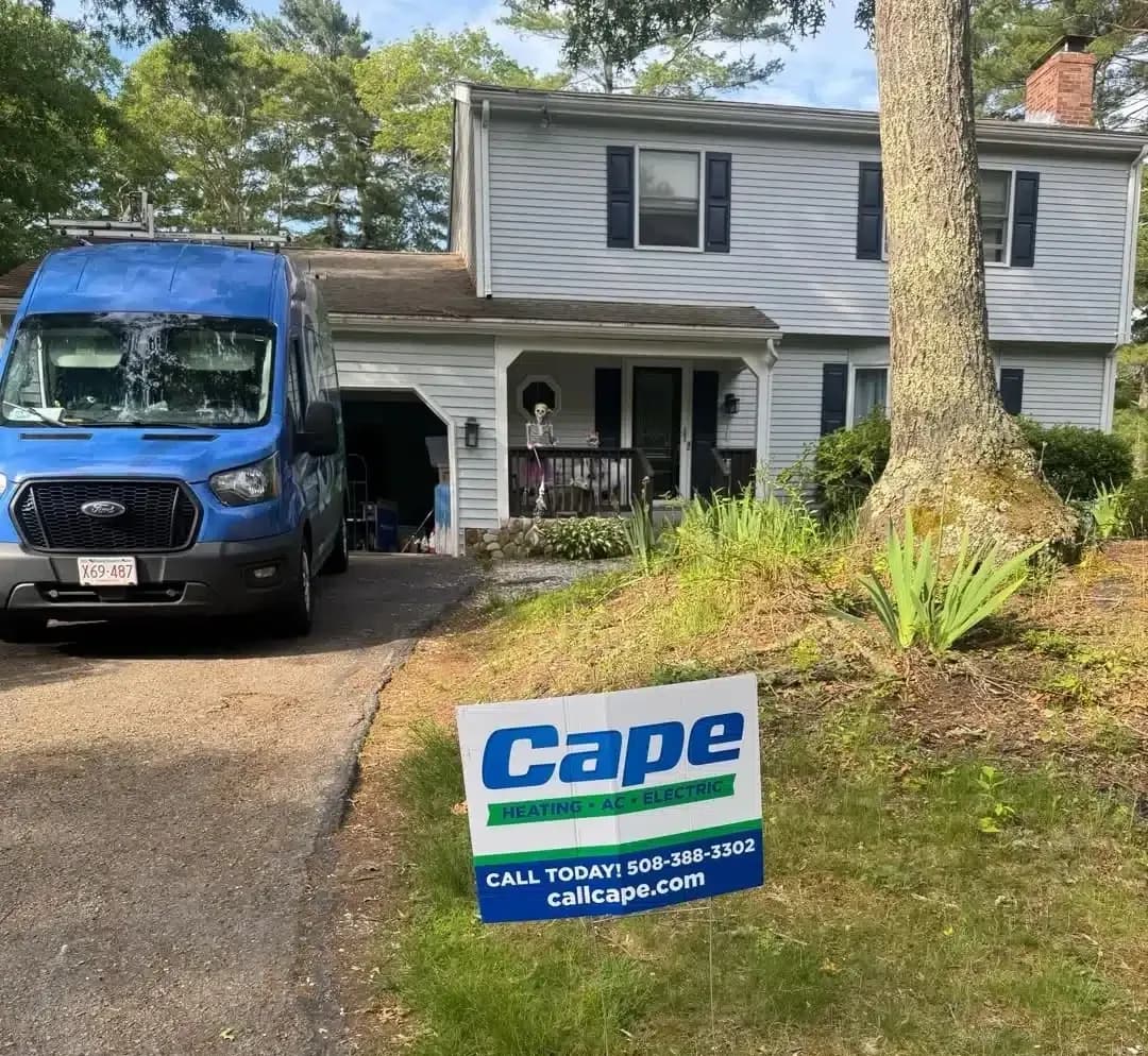 Yard sign for Cape Heating AC & Electric beside a blue service van in a residential Cape Cod, MA driveway