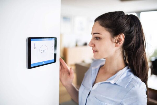 A woman examines her smart thermostat on Cape Cod, MA