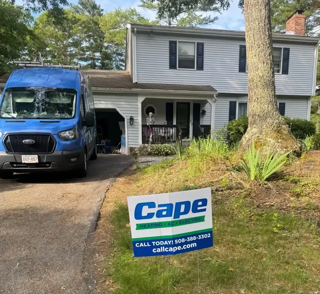 Yard sign for Cape Heating AC & Electric beside a blue service van in a residential Cape Cod, MA driveway