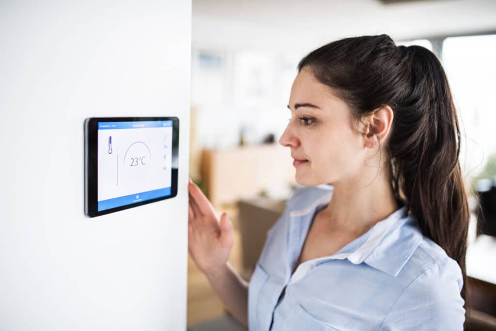 A woman examines her smart thermostat on Cape Cod, MA